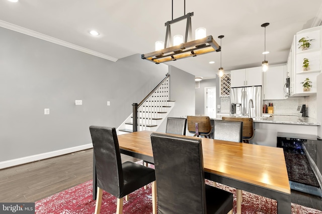 dining room with sink, crown molding, and dark hardwood / wood-style floors