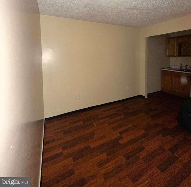 interior space with a textured ceiling, sink, and dark wood-type flooring