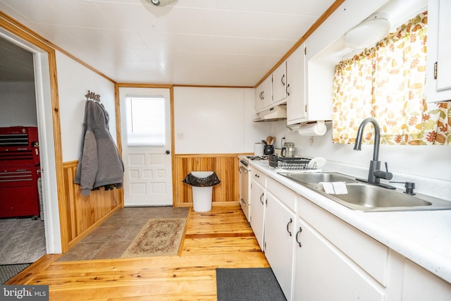 kitchen featuring wood walls, light hardwood / wood-style floors, sink, white cabinetry, and high end stainless steel range oven