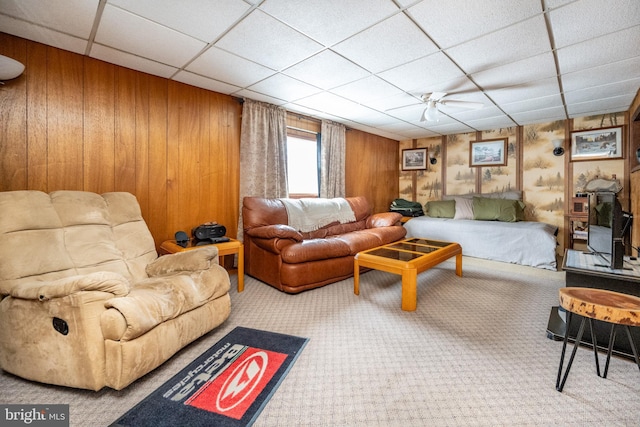 carpeted living room featuring a paneled ceiling and wooden walls