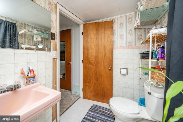 bathroom featuring toilet, sink, tile walls, and tile patterned floors