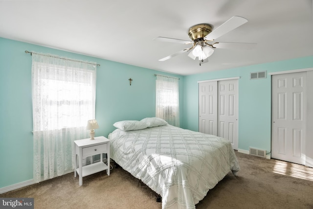 bedroom featuring carpet, ceiling fan, and two closets