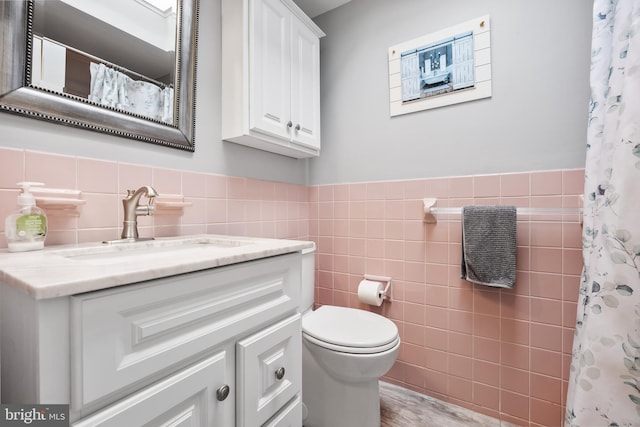 bathroom with a shower with curtain, vanity, toilet, and tile walls