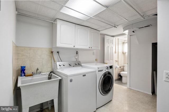 laundry area featuring cabinets, independent washer and dryer, and sink