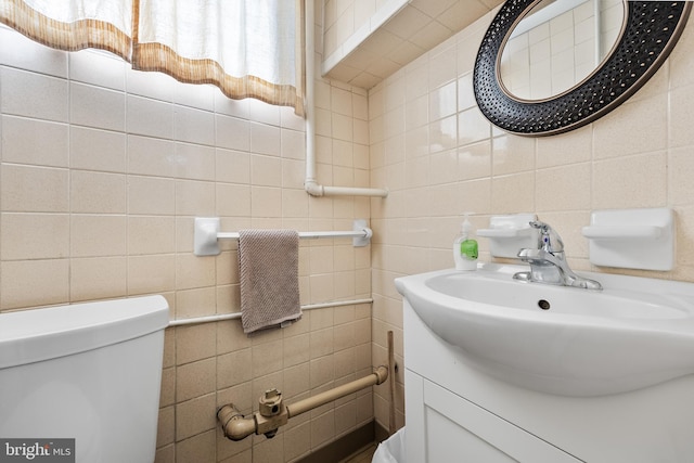 bathroom featuring vanity, tile walls, and toilet