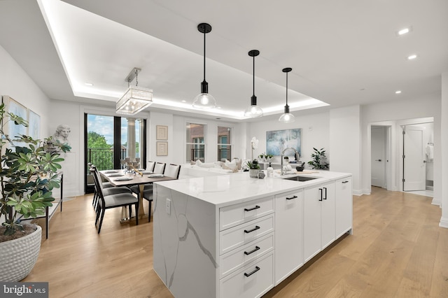 8551 Connecticut Ave Unit 210, Chevy Chase, MD 20815 - kitchen with a tray ceiling, light stone counters, sink, and decorative light fixtures