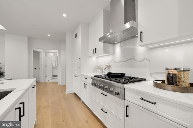 8551 Connecticut Ave Unit 210, Chevy Chase, MD 20815 - kitchen with light stone counters, white cabinetry, stainless steel gas stovetop, and wall chimney range hood