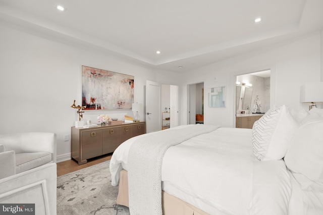 8551 Connecticut Ave Unit 210, Chevy Chase, MD 20815 - bedroom with light wood-type flooring, a tray ceiling, and ensuite bath