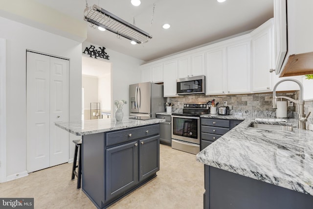 kitchen featuring appliances with stainless steel finishes, a center island, white cabinets, and sink