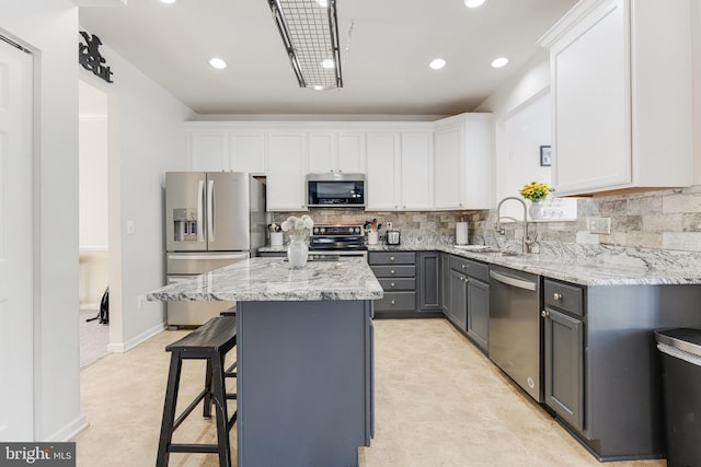 kitchen featuring sink, white cabinets, a kitchen island, gray cabinetry, and appliances with stainless steel finishes