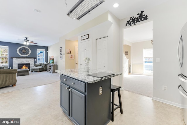 kitchen featuring a kitchen island, ceiling fan, a wealth of natural light, and a breakfast bar area