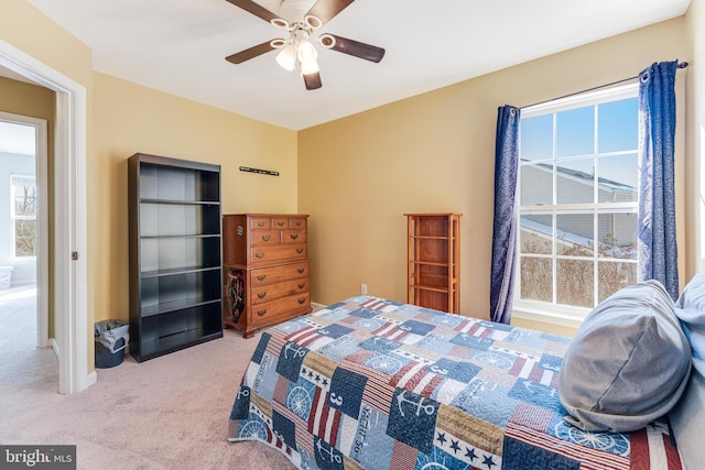 bedroom featuring light colored carpet, ceiling fan, and multiple windows