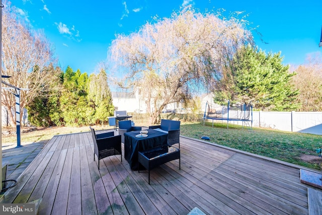 deck with outdoor lounge area, a yard, and a trampoline