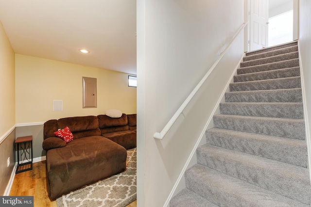 stairs with electric panel and hardwood / wood-style flooring