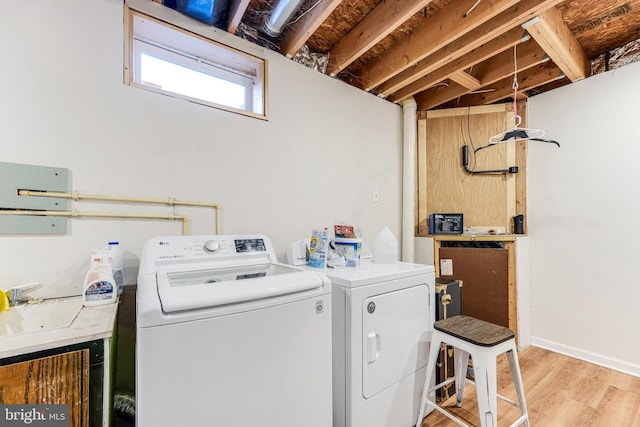 laundry area featuring independent washer and dryer, light hardwood / wood-style flooring, and sink