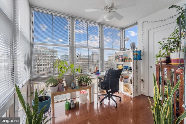 home office with a textured ceiling, a city view, wood finished floors, a ceiling fan, and expansive windows