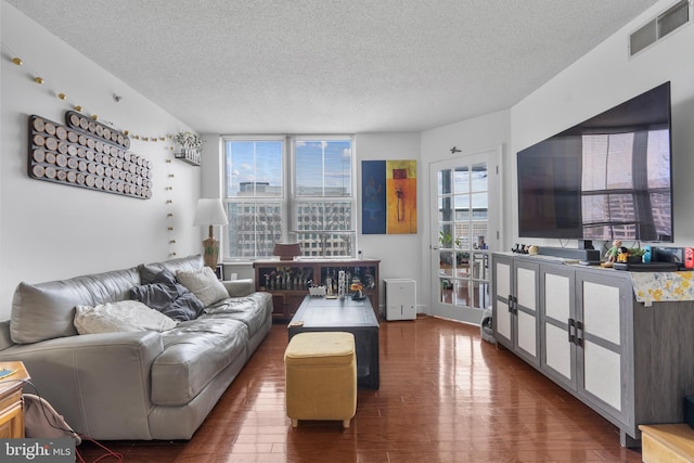 living room with a textured ceiling, visible vents, and wood finished floors