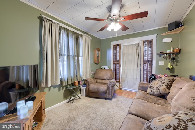 carpeted living room with ceiling fan and ornamental molding