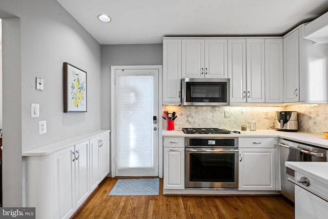 kitchen featuring white cabinets, backsplash, appliances with stainless steel finishes, and dark wood-type flooring