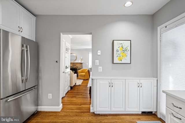 kitchen with white cabinetry, stainless steel refrigerator, and light hardwood / wood-style flooring