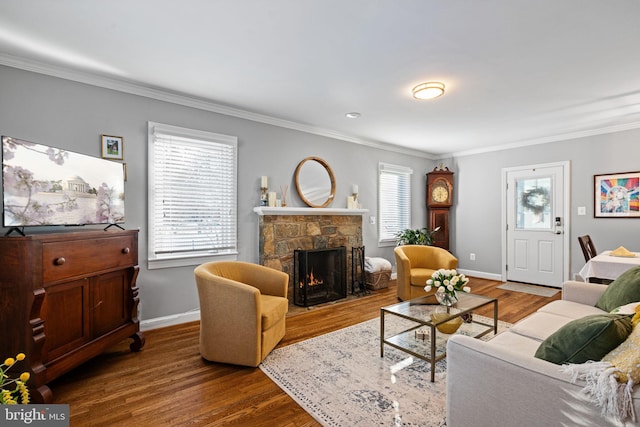 living room with hardwood / wood-style floors, a stone fireplace, and crown molding