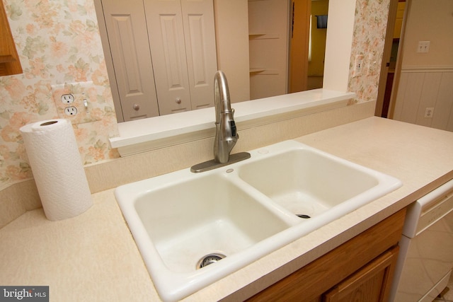 room details with wainscoting, wallpapered walls, light countertops, and a sink