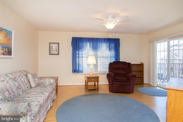 living area featuring baseboards, a ceiling fan, and wood finished floors