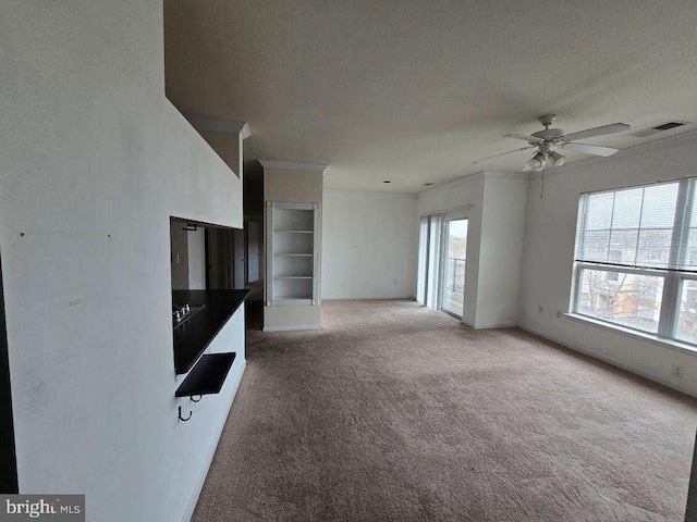 unfurnished living room with ceiling fan, light colored carpet, ornamental molding, and a textured ceiling