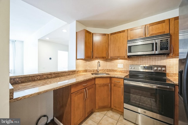 kitchen featuring light tile patterned floors, stainless steel appliances, light stone counters, and sink