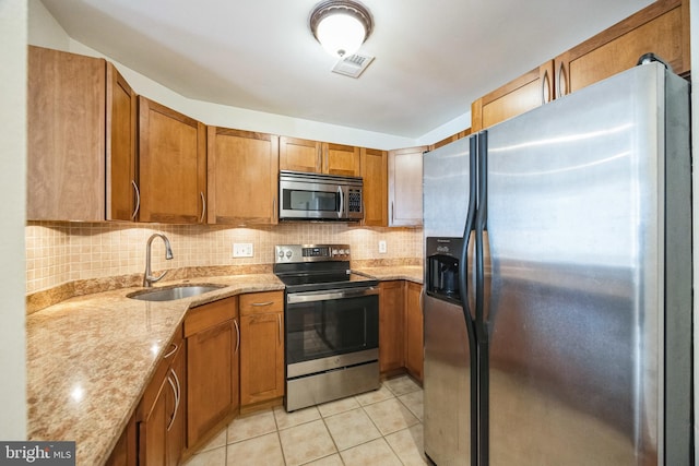 kitchen with light stone countertops, sink, stainless steel appliances, backsplash, and light tile patterned floors