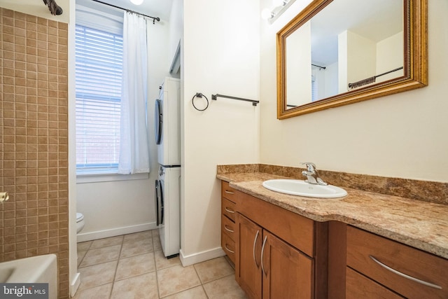 bathroom featuring toilet, vanity, tile patterned floors, and stacked washer / drying machine