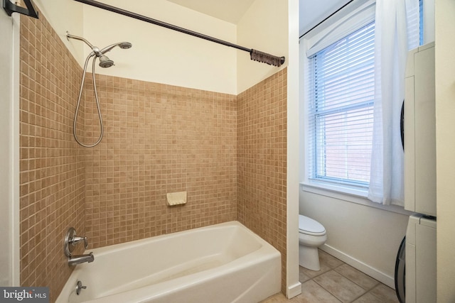 bathroom featuring tile patterned floors, tiled shower / bath combo, toilet, and washer / dryer