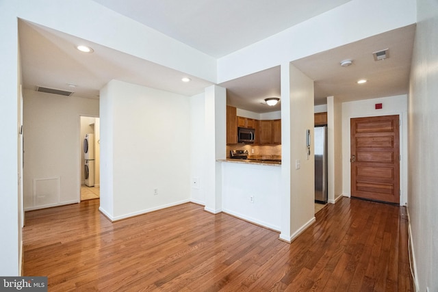 interior space with backsplash, dark hardwood / wood-style floors, and appliances with stainless steel finishes