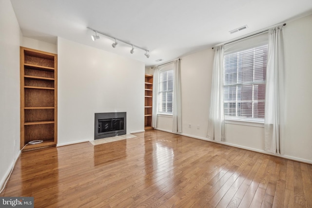 unfurnished living room with built in features and light wood-type flooring