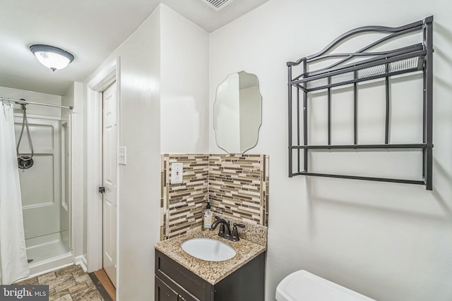 bathroom featuring vanity, curtained shower, toilet, and tasteful backsplash