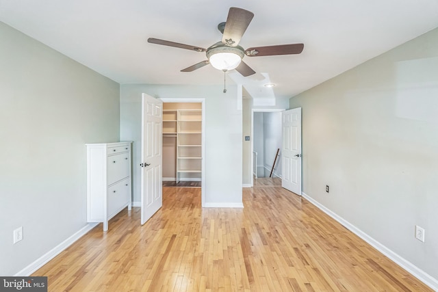 unfurnished bedroom featuring ceiling fan, a spacious closet, light hardwood / wood-style flooring, and a closet