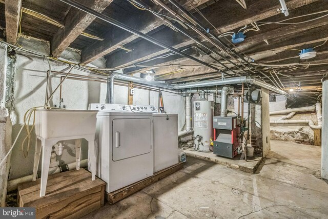 basement with gas water heater, washer and clothes dryer, and sink