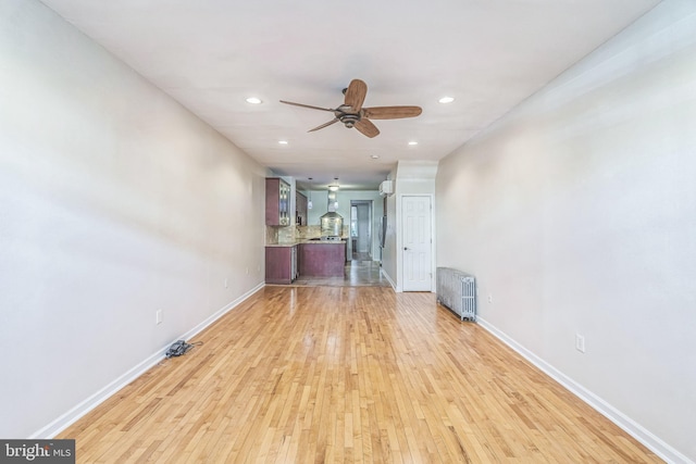 unfurnished living room featuring ceiling fan, radiator heating unit, and light hardwood / wood-style floors