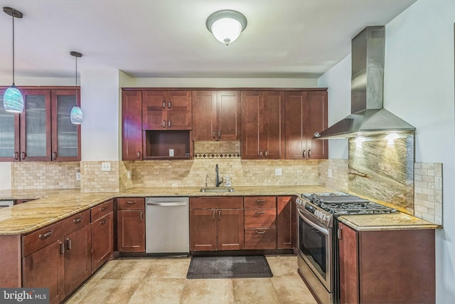 kitchen featuring light stone counters, stainless steel appliances, sink, wall chimney range hood, and pendant lighting