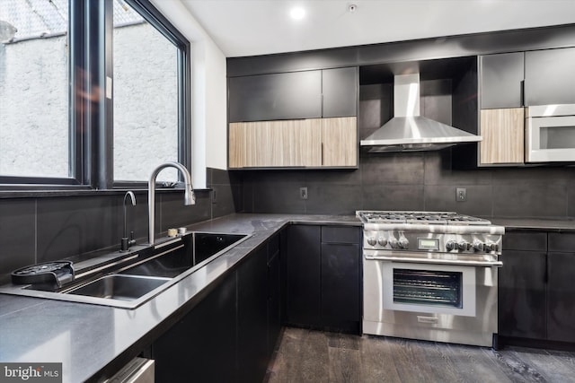 kitchen featuring backsplash, wall chimney range hood, sink, high end stainless steel range oven, and dark hardwood / wood-style flooring