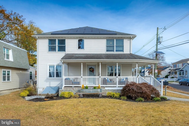 view of front of property with a front yard, solar panels, and covered porch