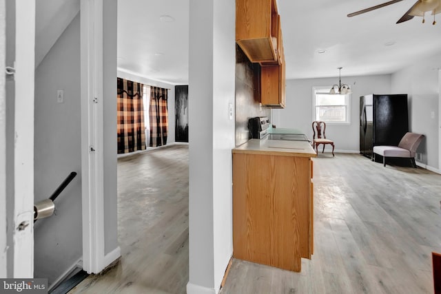 kitchen with range, black fridge, ceiling fan with notable chandelier, decorative light fixtures, and light wood-type flooring