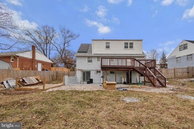 rear view of house with a wooden deck and a lawn