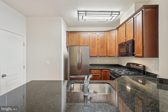 kitchen featuring black appliances, sink, and dark stone counters