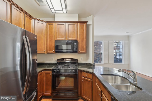 kitchen with kitchen peninsula, crown molding, sink, black appliances, and dark stone countertops