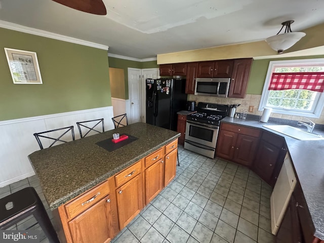 kitchen featuring sink, crown molding, stainless steel appliances, and a kitchen island