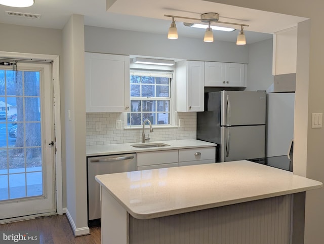 kitchen featuring sink, dark wood-type flooring, stainless steel appliances, backsplash, and white cabinets