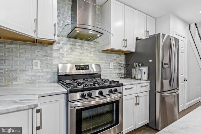 kitchen featuring white cabinetry, wall chimney range hood, light stone counters, and appliances with stainless steel finishes