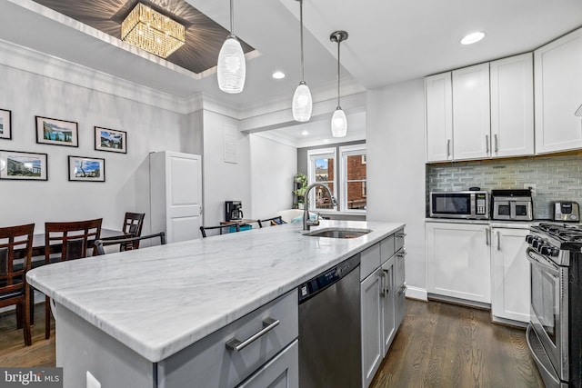 kitchen featuring sink, light stone counters, appliances with stainless steel finishes, an island with sink, and white cabinets