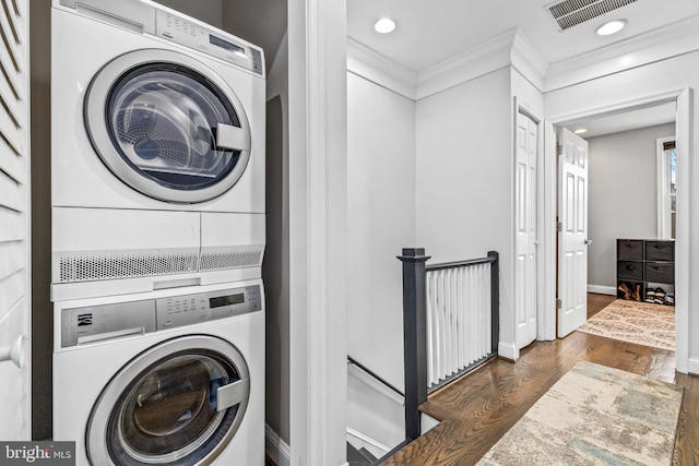 clothes washing area with stacked washer and dryer, crown molding, and dark hardwood / wood-style floors